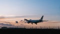 Airplane flying low and fast against a pristine blue sky and a lush green field below at Heathrow Royalty Free Stock Photo