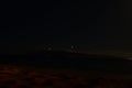 an airplane flying in the night sky over the ocean at beach