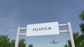 Airplane flying over advertising billboard with Fujifilm logo. Editorial 3D rendering Royalty Free Stock Photo