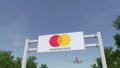 Airplane flying over advertising billboard with MasterCard logo. Editorial 3D rendering