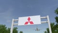 Airplane flying over advertising billboard with Mitsubishi logo. Editorial 3D rendering