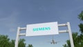 Airplane flying over advertising billboard with Siemens logo. Editorial 3D rendering