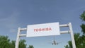 Airplane flying over advertising billboard with Toshiba Corporation logo. Editorial 3D rendering