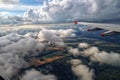 Airplane flying over beautiful dramatic cloudscape with fields forests and sunlight Royalty Free Stock Photo