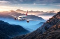 Airplane is flying over mountains in fog at colorful sunset Royalty Free Stock Photo