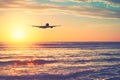 Airplane flying over tropical beach with smooth wave and sunset sky abstract background Royalty Free Stock Photo