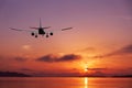 Airplane flying over tropical sea at beautiful sunset or sunrise Royalty Free Stock Photo