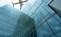 Airplane flying in the sky above modern sustainable glass office building. Exterior skyscraper green glass building. Business Royalty Free Stock Photo