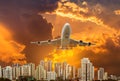 Airplane flying take off from runway on sunset over modern skyscrapers Royalty Free Stock Photo