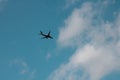 airplane flying in a turquoise sky surrounded by clouds Royalty Free Stock Photo