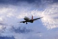 Airplane flying under beautiful evening clouds, front view Royalty Free Stock Photo