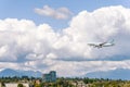 Airplane flying under the clouds over the trees Royalty Free Stock Photo