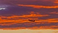Airplane in front of illuminated clouds at afterglow