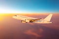 Airplane high in the sky flies on the clouds during the evening light and sunset. Royalty Free Stock Photo