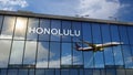 Airplane landing at Honolulu Hawaii, USA airport mirrored in terminal Royalty Free Stock Photo