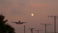 Airplane landing in LAX airport at sunset, Los Angeles, California USA. Passenger flight or cargo plane silhouette, dramatic