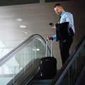 Airplane mode - on. a businessman using a mobile phone while traveling down an escalator in an airport. Royalty Free Stock Photo