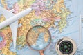 Airplane model, magnifying glass and compass on Japan map Royalty Free Stock Photo