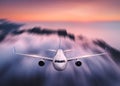 Airplane with motion blur effect is flying over clouds at sunset Royalty Free Stock Photo