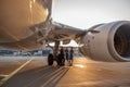 Airplane near the terminal in an airport at the sunset. Pilot and two stewardesses standing together and talking after Royalty Free Stock Photo