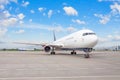 Airplane parked at the airport against the backdrop of a blue scenic skyline with clouds. World aviation concept