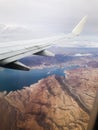 airplane passenger view of wing flying over water mountains and desert Royalty Free Stock Photo