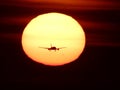 Airplane descending to land at BCN airport and crossing the sun at sunrise Royalty Free Stock Photo