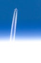Airplane seen from below with white contrails in a clear blue sky with gradient from blue to white with copy-space Royalty Free Stock Photo