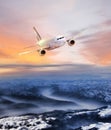 Airplane in the sky over winter Alps at amazing colorful sunset