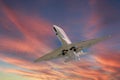 Airplane in the sky at sunrise or sunset. Small business jet is flying with lights and deployed landing gear preparing for landing Royalty Free Stock Photo