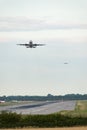 An airplane takes off as others come into land in an aircraft landing queue behind, with other planes waiting next to the runway