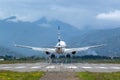 Airplane touching down the runway. Mountains and clouds background. Royalty Free Stock Photo