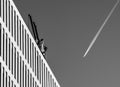 Airplane trail forming a V shape with modern office building and a crane. Royalty Free Stock Photo