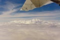 Airplane transport concept. View on the left wing passenger aircraft.Below the thick clouds illuminated by the sun.Horizontal view Royalty Free Stock Photo