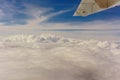 Airplane transport concept. View on the left wing passenger aircraft.Below the thick clouds illuminated by the sun.Horizontal view Royalty Free Stock Photo