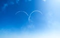 Airplane with white smoke trail in his heart from jet planes against cloudy blue sky.