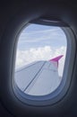 Airplane window and wing in cloudy sky Royalty Free Stock Photo