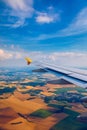 Airplane windows view above the earth on landmark down. View from an airplane window over a wing flying high above farmlands and Royalty Free Stock Photo