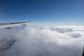 Airplane wing above cloud under clear blue sky.