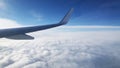 Airplane wing on a background of blue sky and clouds. View in flight above cloud level. Royalty Free Stock Photo