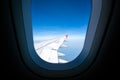 Airplane wing on blue sky, view through plane window, with copy space