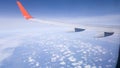 An airplane wing, bright blue sky and small feather clouds. Flight on a passenger plane. View through the porthole Royalty Free Stock Photo