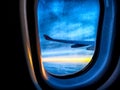 Airplane wing, clouds and sunrise through plane window. Wing silhouetted against vibrant sunset sky. Sunset Horizon View Royalty Free Stock Photo