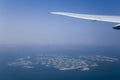 Airplane Wing and Clouds Viewed from Inside the Aircraft, with Dubai The World Islands in background. Travel concept with copy Royalty Free Stock Photo