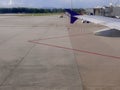 Airplane wing with docked ladder at the airport field apron, taxiway with red line marking Royalty Free Stock Photo