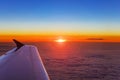 Airplane wing in flight above the clouds at the sunset background