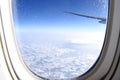 Airplane wing flying above clouds in blue sky, view from airplane window Royalty Free Stock Photo