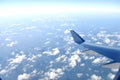 Airplane wing flying above clouds in blue sky, view from airplane window Royalty Free Stock Photo