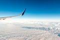 Airplane wing over cloudy mountains