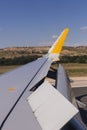 Airplane wing on the runway at airport on a sunny day. Flaps up. Travel and holidays concept. view from the passengers window Royalty Free Stock Photo